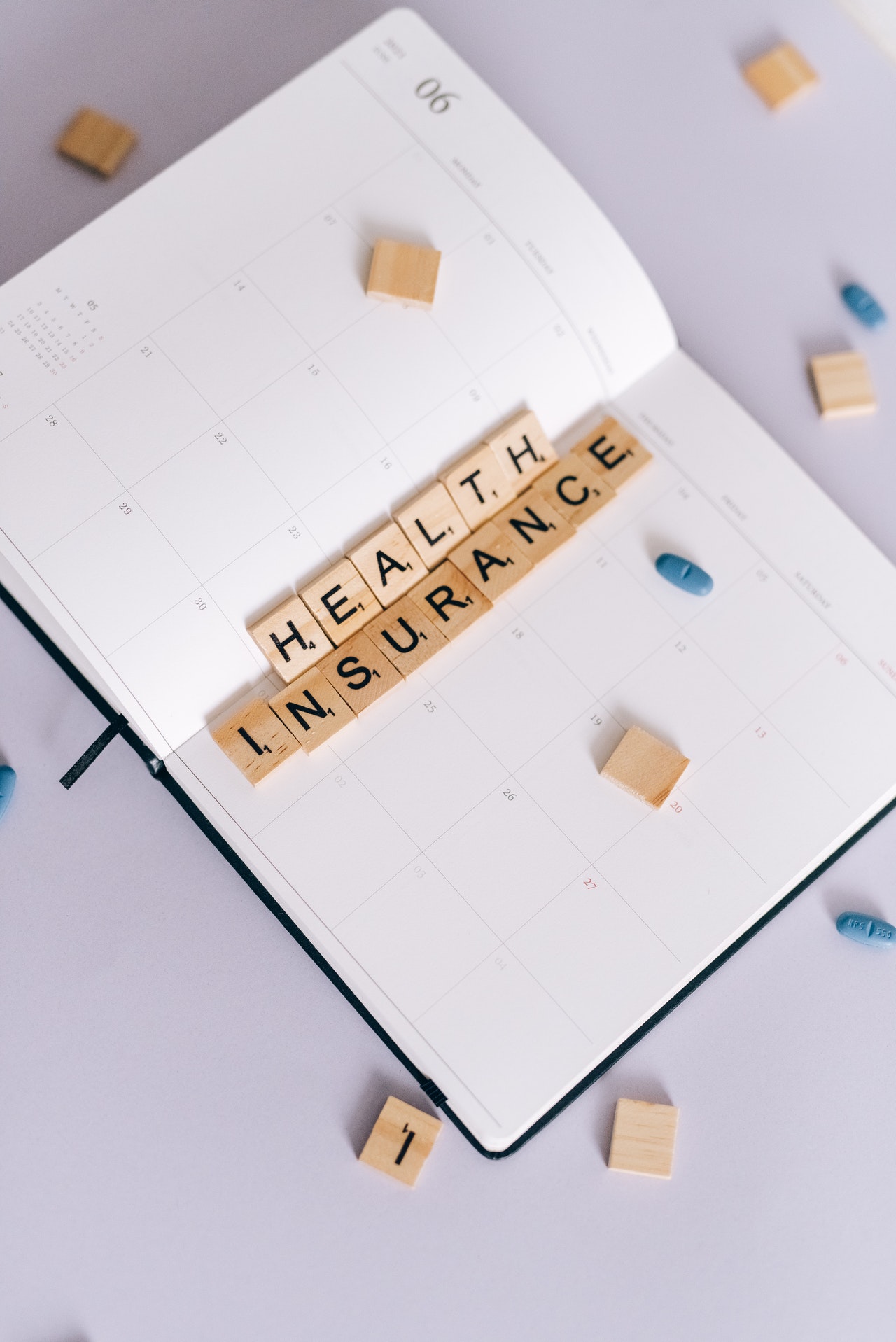 Health Insurance Spelled on Scrabble Blocks on Top of a Notebook Planner